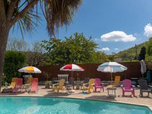 a group of chairs and umbrellas next to a pool at Le Castel d'olmes in Laroque-dʼOlmes