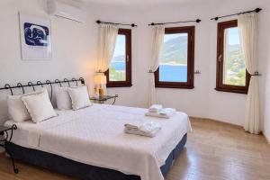 a bedroom with a large bed and two windows at Villa Noa Amazing Sea view in Kaş