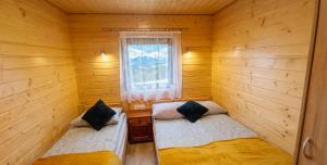 two beds in a room with a window at Bieszczadzkie domki z widokiem 793-903-243 in Bukowiec