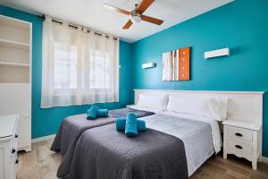 two beds in a bedroom with blue walls at Apartamentos Eldorado in Lloret de Mar +48 photos