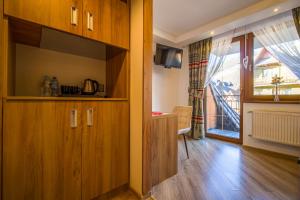 a kitchen with wooden cabinets and a large window at Residence Spa Harenda in Zakopane +98 photos