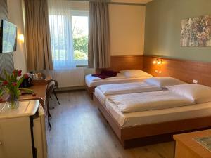 a hotel room with two beds and a desk at Hotel Oyten am Markt Bremen in Oyten