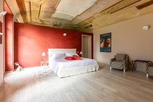 a bedroom with a white bed and a red wall at OLIVOLA APARTMENTS in Frassinello +29 photos