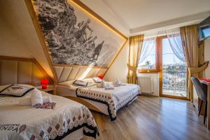 a hotel room with two beds and a painting on the wall at Residence Spa Harenda in Zakopane