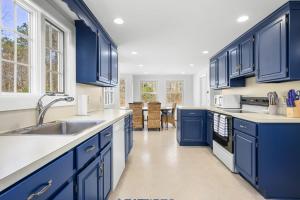 a blue kitchen with white counters and blue cabinets at The Salty Dolphin - DEN - DW7 in Dennis