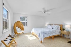 a bedroom with a bed and a chair and windows at The Salty Dolphin - DEN - DW7 in Dennis