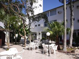 a patio with white tables and chairs in front of a building at HANNA Marina's Palace Hotel in Florianópolis