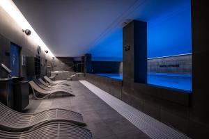 a bathroom with a swimming pool and a row of benches at Lumina OVO2 in Wrocław