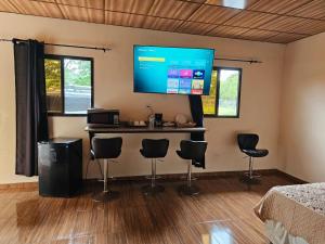a room with a bar with chairs and a flat screen tv at Tocumen Comfort Stay in Aserrío