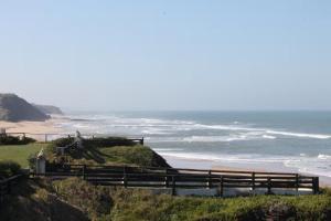 a person riding a horse on a hill next to a beach at Sweet West in Lourinhã
