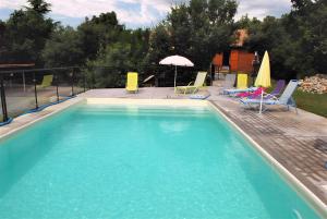 a swimming pool with chairs and umbrellas on a patio at Mas du soleil levant in Les Vans