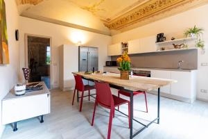 a kitchen with a large wooden table and red chairs at OLIVOLA APARTMENTS in Frassinello