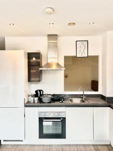 a kitchen with white cabinets and a sink at Digbeth Luxury 1 Bed Studio Apartment in Birmingham