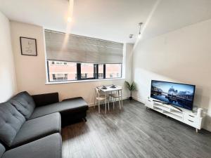 a living room with a couch and a flat screen tv at Digbeth Luxury 1 Bed Studio Apartment in Birmingham