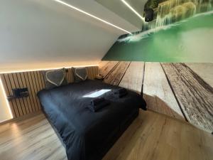 a bedroom with a bed and a wooden floor at Studio détente, sdb privative, billard, air soccer, clim in Verviers