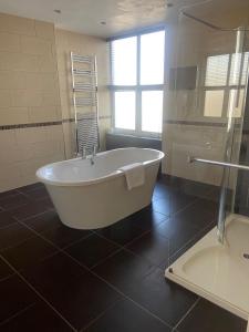 a bathroom with a bath tub and a shower at The Windsor House Hotel in Worthing +17 photos
