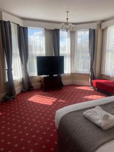 a hotel room with a bed and a flat screen tv at The Windsor House Hotel in Worthing