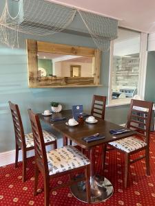 a dining room table with chairs and a mirror at The Windsor House Hotel in Worthing