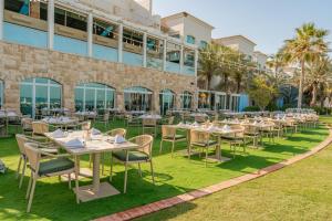 a restaurant with tables and chairs in front of a building at Mövenpick Hotel & Resort Al Bida'a in Kuwait