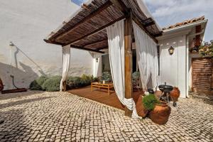 a house with a wooden deck with curtains on it at Casa Do Canto in Cascais
