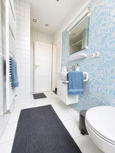 a bathroom with a white toilet and blue tiles at Ferienwohnung Nikolaiblick in Stralsund