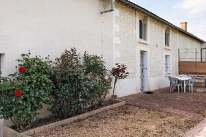 a house with a garden with red flowers and a table at Gîte La Chapelière in Assay
