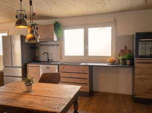 a kitchen with a wooden table and a kitchen with a refrigerator at Bodensee Living Ferienwohnung Wald in Wald