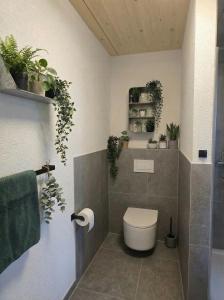 a bathroom with a toilet and plants on the wall at Bodensee Living Ferienwohnung Wald in Wald
