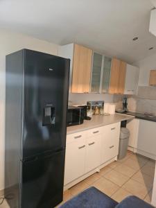 a black refrigerator in a kitchen with white cabinets at Appartement T2 in Vaugneray