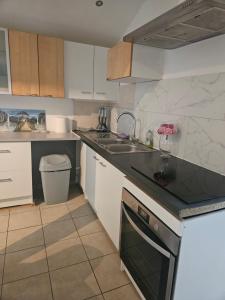 a kitchen with white cabinets and a black counter top at Appartement T2 in Vaugneray
