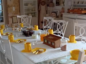 a white table with yellow napkins and plates on it at Le chant des oiseaux in Ryes