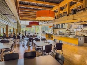 a restaurant with tables and chairs and people in the kitchen at Auberge de Jeunesse Val-de-Travers in Couvet