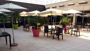 an outdoor patio with tables and chairs and umbrellas at Residhome Suites Paris Sénart in Lieusaint
