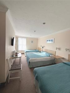 a hotel room with three beds and a television at Eastbourne Riviera Hotel in Eastbourne +57 photos