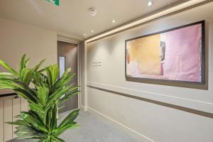 a plant in a hallway with a painting on the wall at The Maida Hotel in London