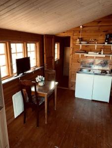 a room with a table and a kitchen in a cabin at Cabin at the Gate to Österlen in Degeberga