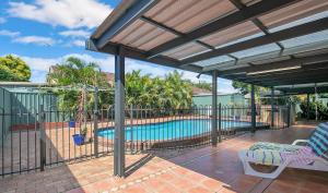a patio with a swimming pool and a deck with a pergola at Spacious home with pool in Kippa-Ring in Newport