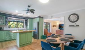a kitchen with a table and a clock on the wall at Spacious home with pool in Kippa-Ring in Newport