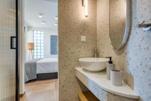 a bathroom with a sink and a bedroom at TINY HOUSE STUDIO AT COURTYARD COTTAGE CORFu in Lákones
