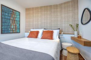 a bedroom with a bed with orange pillows and a mirror at TINY HOUSE STUDIO AT COURTYARD COTTAGE CORFu in Lákones +22 photos