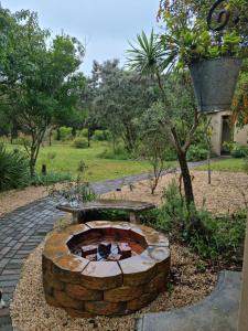 a brick fire pit with a bench in a garden at Little Louisa in Port Elizabeth