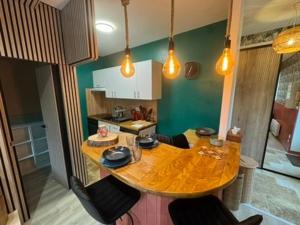 a kitchen with a wooden table and some lights at Séjour Château Moderne avec Cinéma in Verberie