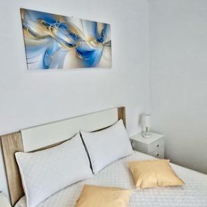 a bedroom with a bed with a painting on the wall at Vila de Baixo in Lajes das Flores