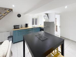 a kitchen with blue cabinets and a black table at Le Petit Curie in Gien +25 photos