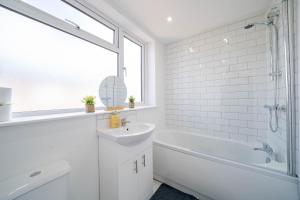 a white bathroom with a sink and a bath tub at Spacious 3 Bedroom House in Ashton-under-Lyne by Eason Stays with Free Parking and Courtyard View in Stalybridge +54 photos