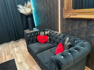 a black couch with two red pillows on it at Chambre business-romantique, jacuzzi, billard, clim in Verviers +31 photos