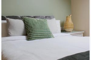 a white bed with a green pillow on top of it at 1 Bed Loft - Sleeps 2 - Parking - Wifi in Newport