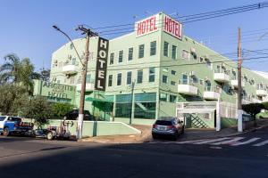 a green building with a car parked in front of it at Argentin Palace Hotel in Americana