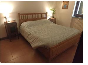 a bedroom with a wooden bed and two night stands at Casa Lu' in Bosisio Parini