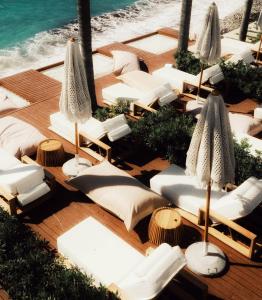a deck with chairs and umbrellas and the ocean at Oniro by Iliria Palace in Himare